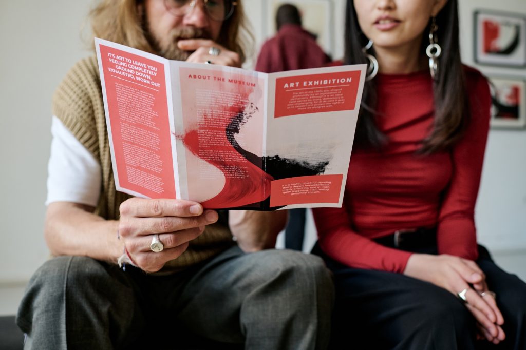 Discussing Art Exhibition Pamphlet While Sitting Together
